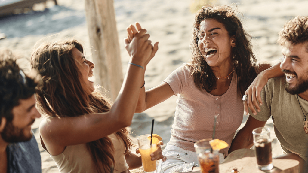 Άνθρωποι γελούν πίνοντας ποτά σε beach bar